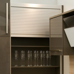 Aluminium Smart Box roller shutter concealing glassware storage in a modern kitchen cabinet