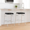 Pair of stainless steel kitchen bar chairs with black cushioned seats at a modern white kitchen counter