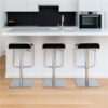 Three Waterfall stainless steel bar chairs with black seats lined up at a white kitchen island