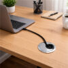 Round chrome cable grommet with brush insert managing cable on office desk