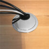 Chrome round cable grommet with brush insert managing multiple cables on wooden desk